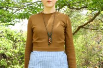 Close-up of brown sweater and beaded pendant necklace